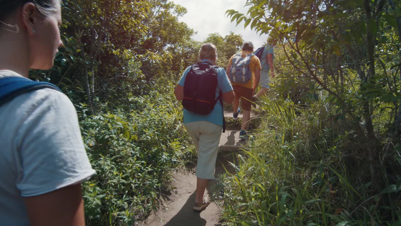 一家人在热带森林里徒步旅行。带着孩子的大家庭探索小径，在郁郁葱葱的丛林中徒步旅行视频素材