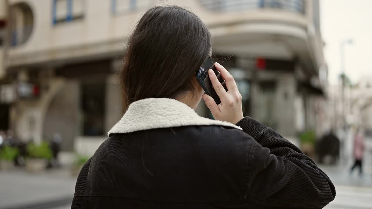 年轻漂亮的西班牙女人在街上用智能手机聊天视频素材