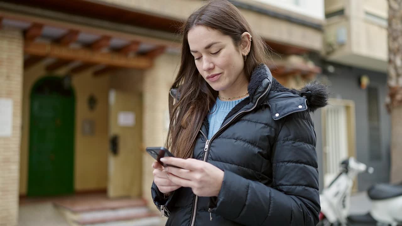 年轻的白人女子在街上用智能手机自信地微笑着视频素材