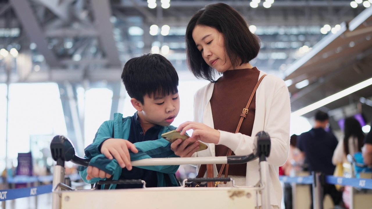 现代交通技术使旅行方便快捷。母子俩在服务台准备护照和行程电子机票办理登机手续。一名女子站在机场的行李车旁。视频素材