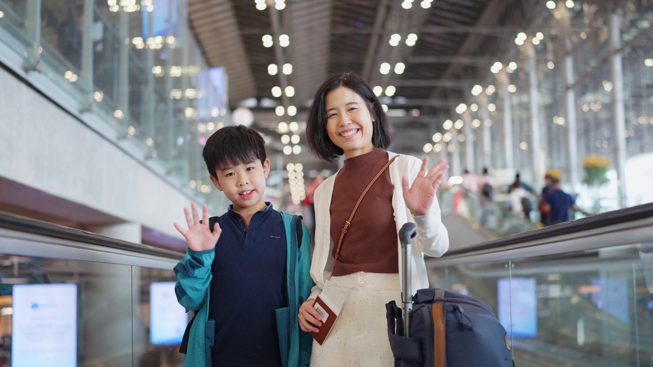 通过出国旅行积累经验。母子俩站在自动扶梯上，对着镜头挥手道别。一名女子拿着护照和行李，准备去机场办理登机手续。假期旅行。视频素材