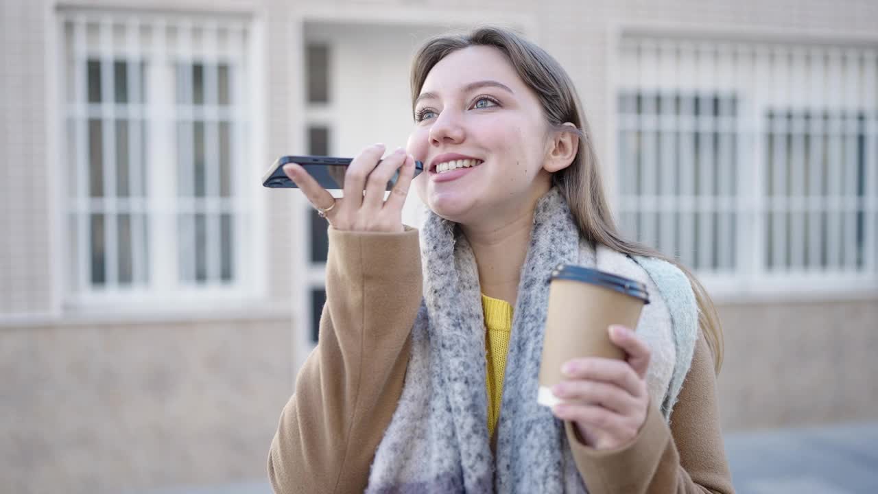 年轻的金发女子在街上用智能手机聊天，喝咖啡视频素材