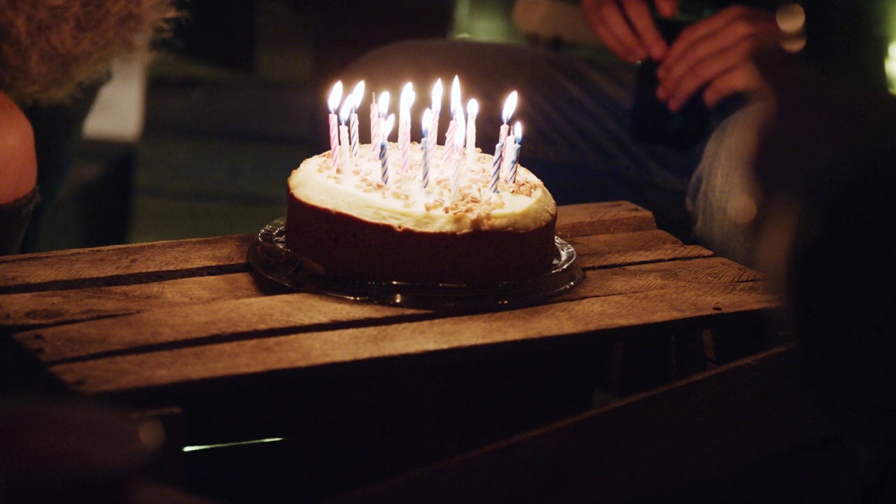 一群朋友晚上在屋顶庆祝生日聚会，美丽的年轻女子吹蜡烛，享受友谊，分享快乐的庆祝活动视频素材