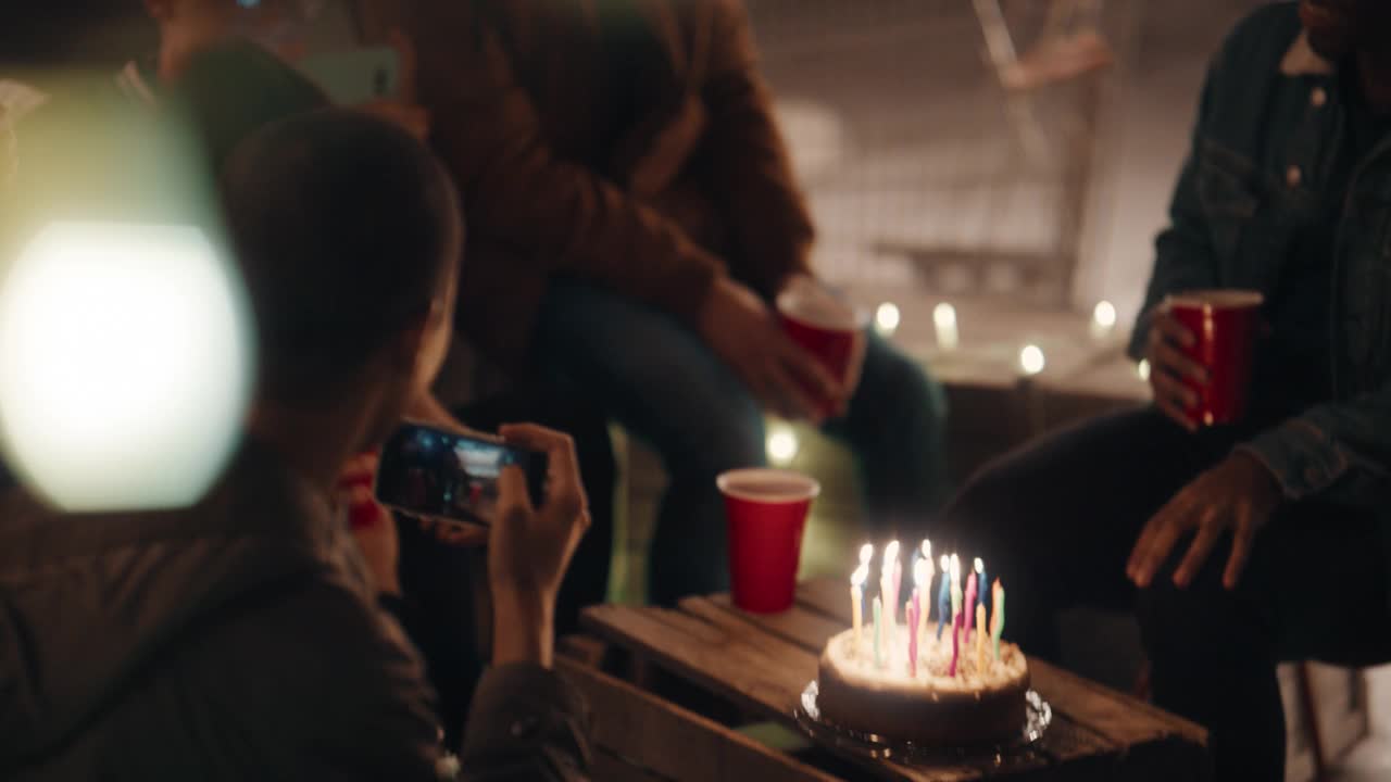 一群快乐的朋友晚上在屋顶庆祝生日聚会，美丽的年轻女子吹蜡烛，享受友谊，分享快乐的庆祝活动视频素材