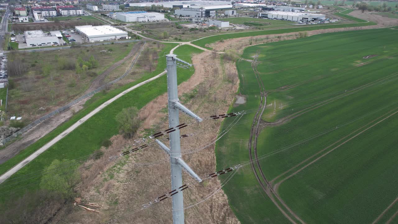 从高空俯瞰高压电线和陶瓷绝缘子与城市天际线和工业区。视频素材