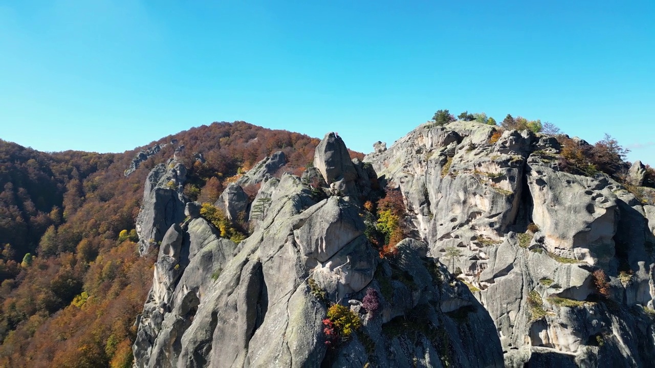 在一个阳光明媚的日子里，无人机在森林山脉和岩石山丘上的场景视频素材