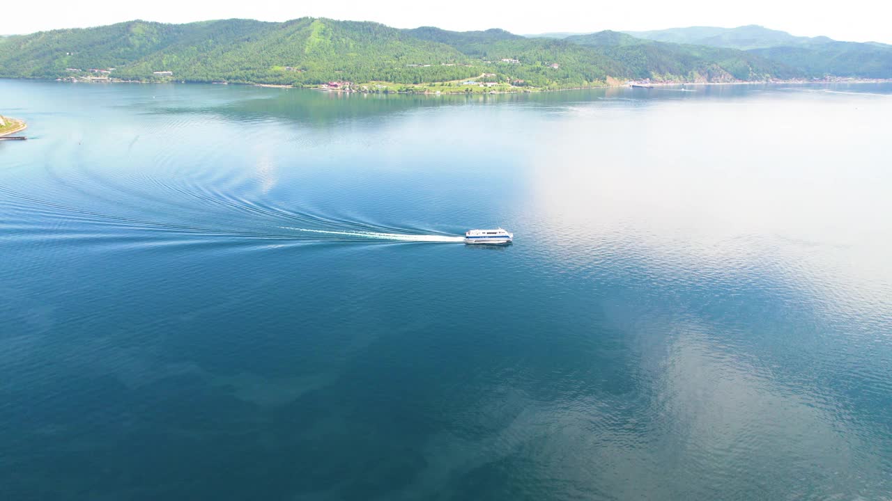 一艘载着游客的船沿着贝加尔湖行驶。从空中俯瞰Listvyanka村。视频素材