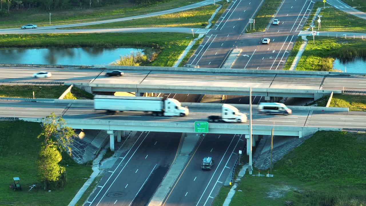 日落时美国农村高速公路立交桥交叉口快速移动的车辆和卡车鸟瞰图。美国州际交通基础设施视频素材