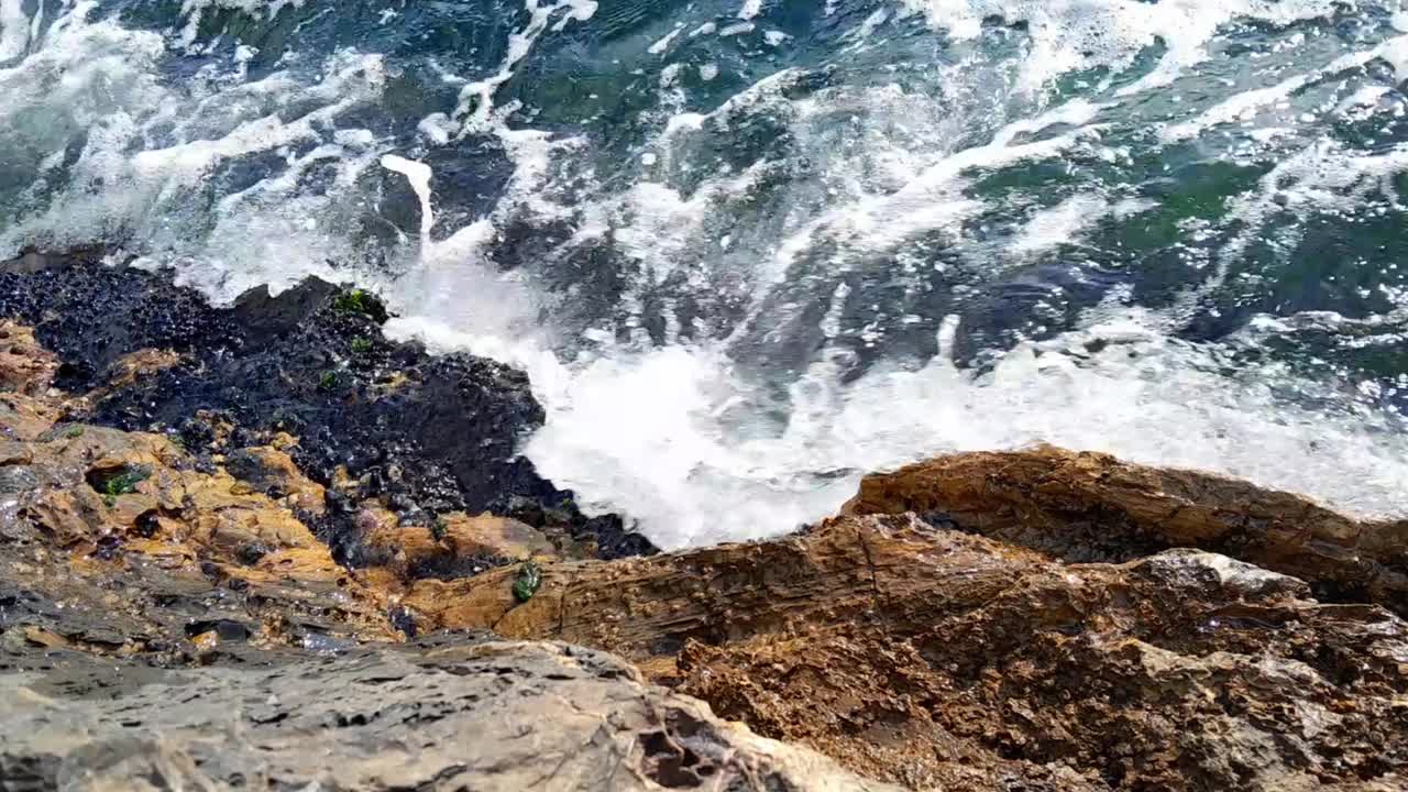 海浪拍打着长满青苔的岩石视频素材