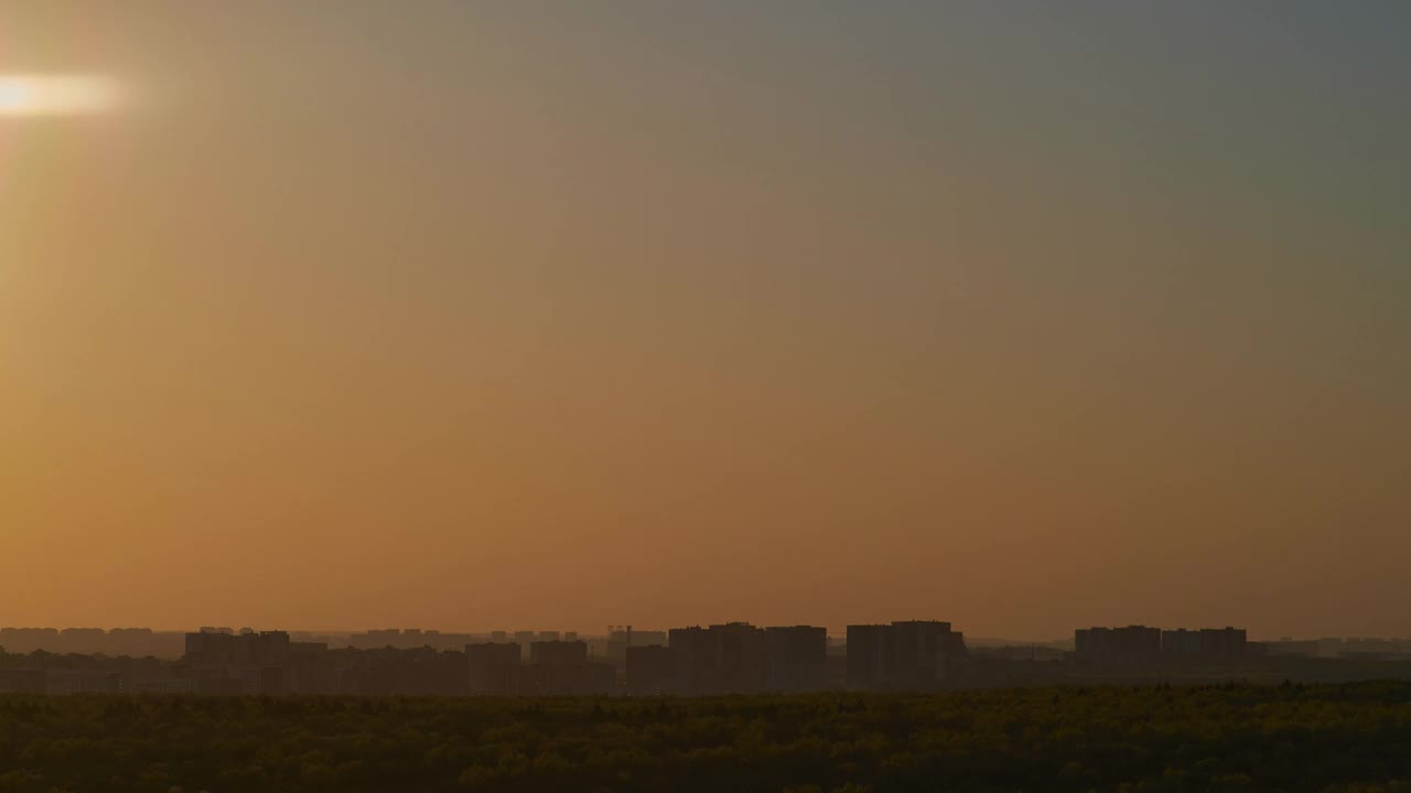 夕阳在城市高楼的窗户上投下火红的倒影。当太阳落在云层后面时，城市上空的云层染上了粉红色和紫色的阴影。视频素材