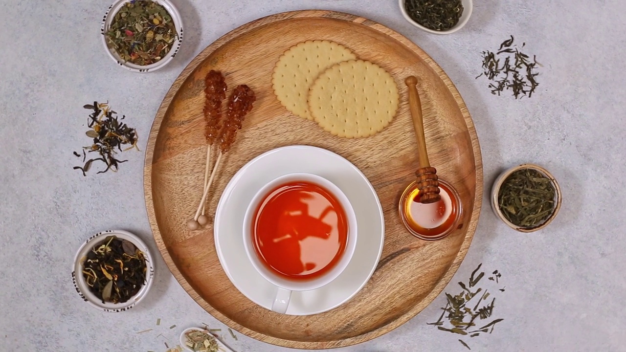 白杯红茶，干红茶和饼干。用陶瓷勺子晒干各种茶叶。白石背景视频下载