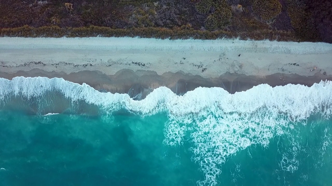 海滩和海浪的鸟瞰图，白色的沙滩和蓝色的大海。关于假期和旅行视频素材