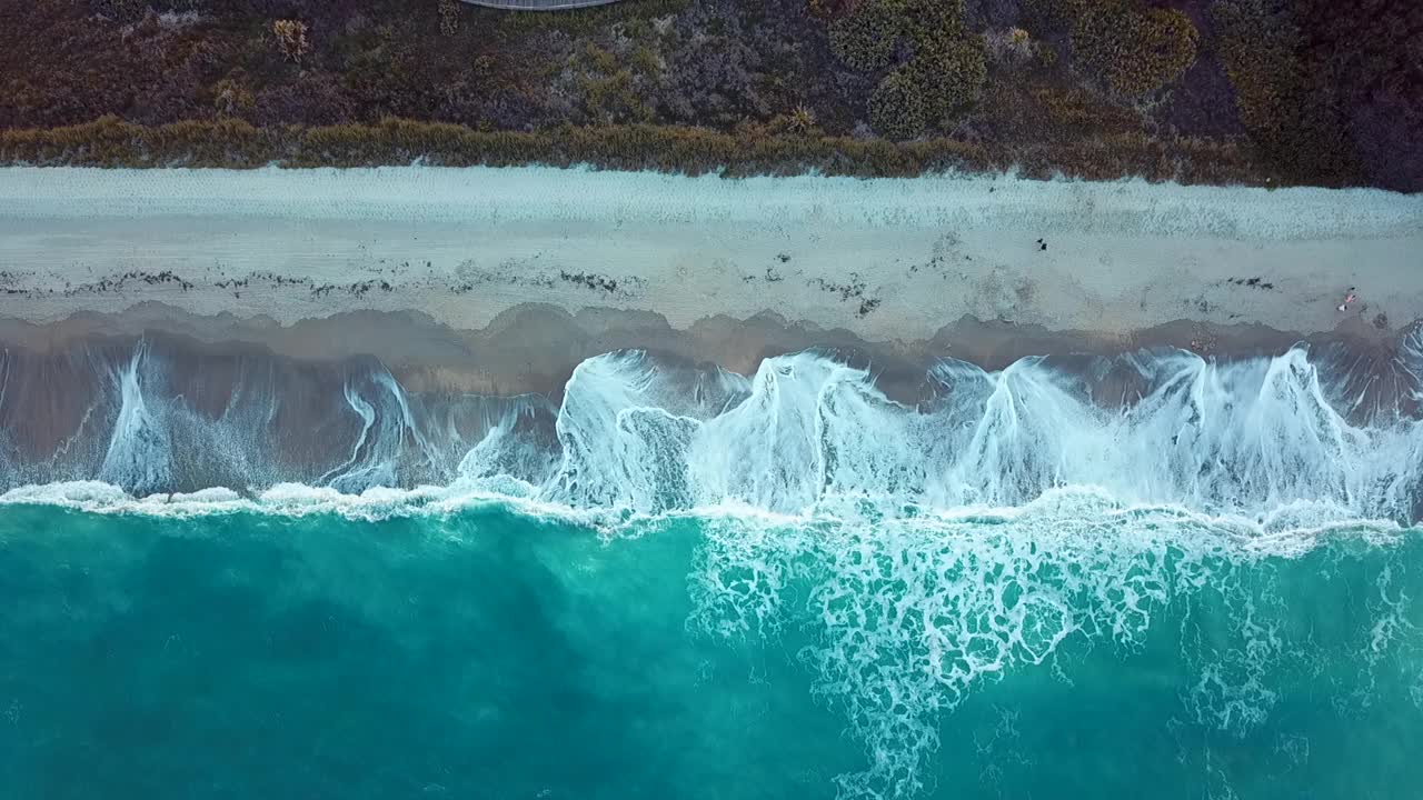 海滩和海浪的鸟瞰图，白色的沙滩和蓝色的大海。关于假期和旅行视频素材