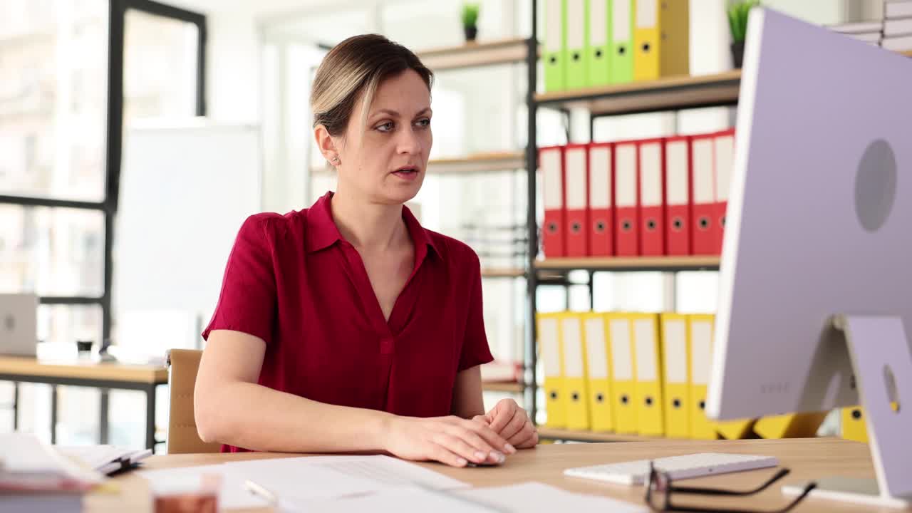 坐在办公室桌子旁的女商人摸了摸手腕，感到疼痛视频素材