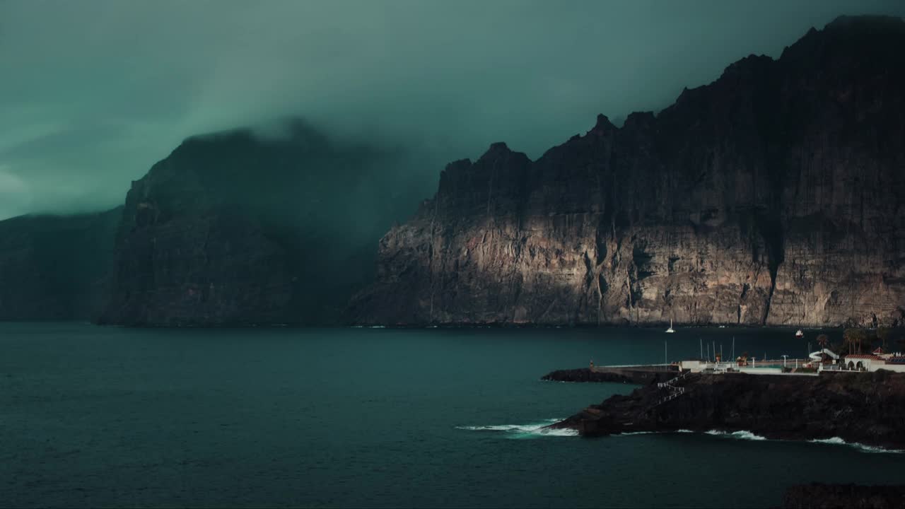 黑暗的海洋景观，黑色火山悬崖上的灰色风暴云。大雾覆盖了特内里费岛的海岩。神秘的雾霾是一种自然现象。视频素材