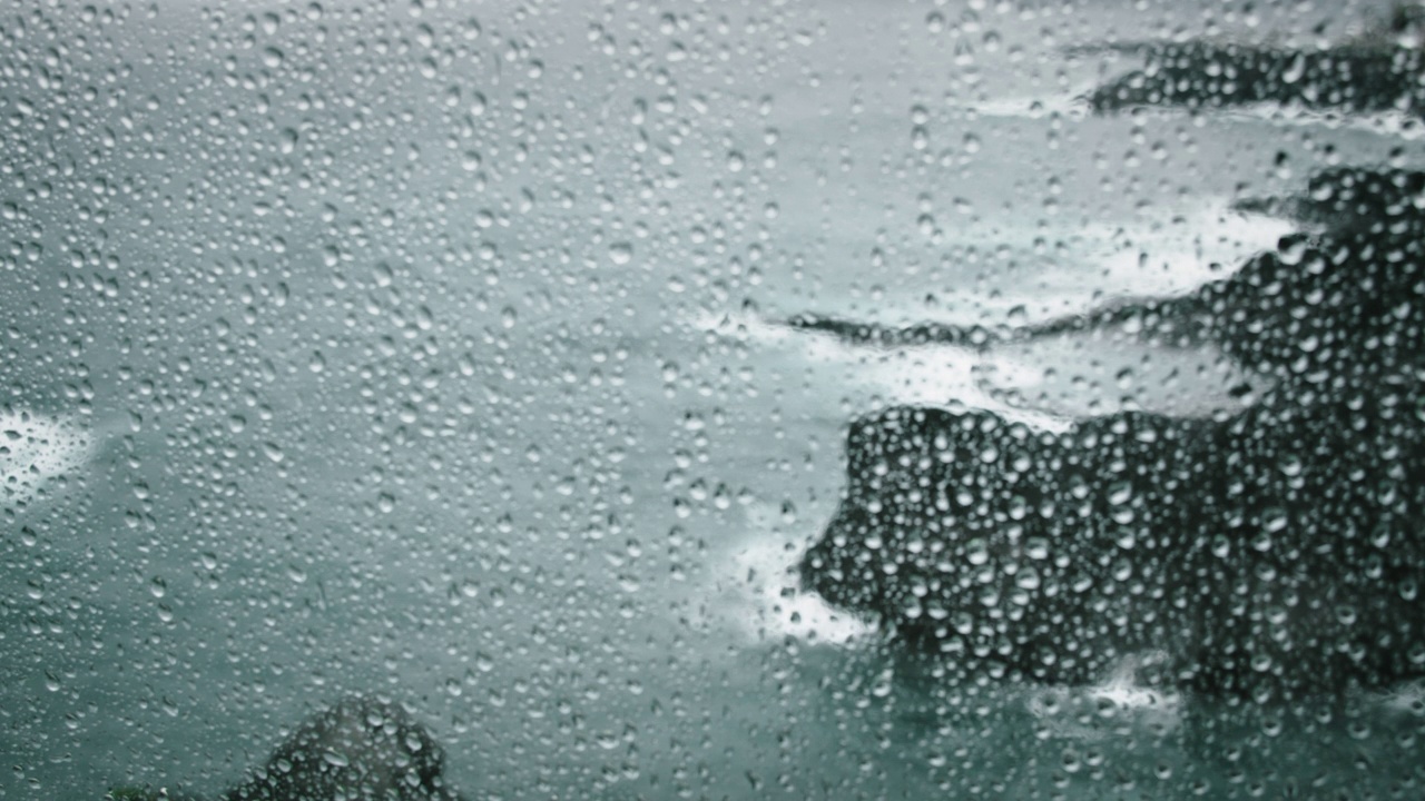 雨滴落在窗户透明玻璃抽象的背景。灰暗的海洋景观和灰色的风暴云。雾笼罩着海岸上高高的海崖。视频素材