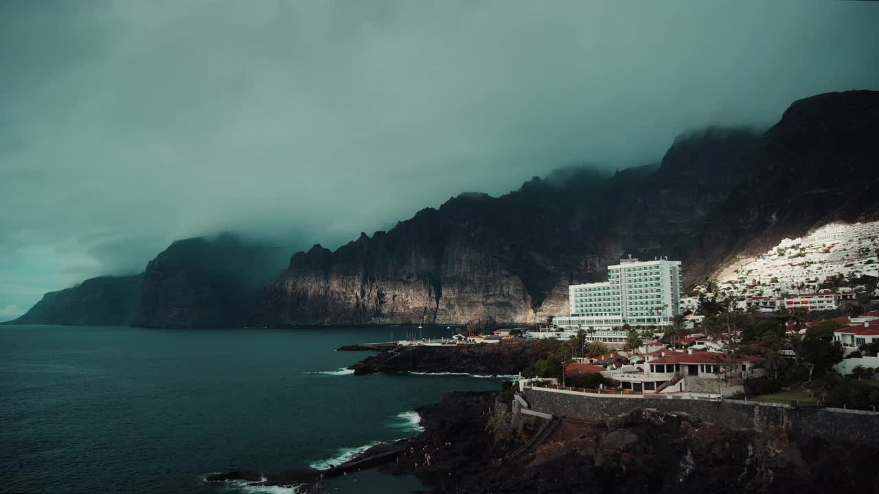 戏剧性的黑暗风暴海洋景观。月亮透过云层照耀在岩石海岸线的洛斯吉安蒂斯悬崖上。视频素材