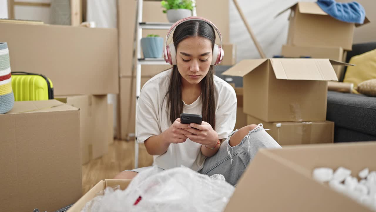 年轻漂亮的西班牙女子坐在新家的地板上听音乐跳舞视频素材