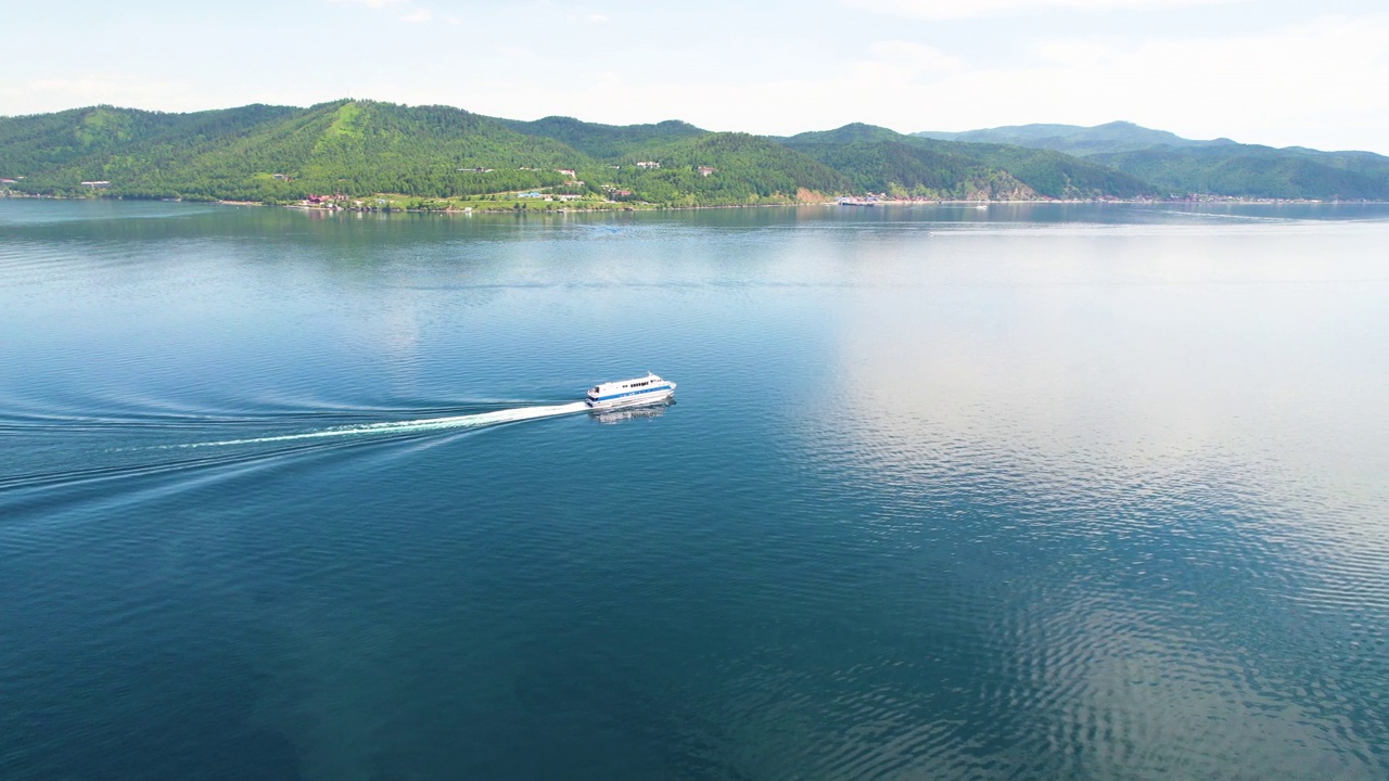 一艘载着游客的船沿着贝加尔湖行驶。从空中俯瞰Listvyanka村。视频素材