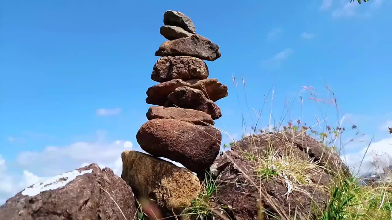 印尼南苏拉威西巴鲁马多山山顶的石堆平衡的视频，正午的蓝天背景。平衡的概念，稳定，稳定。视频下载