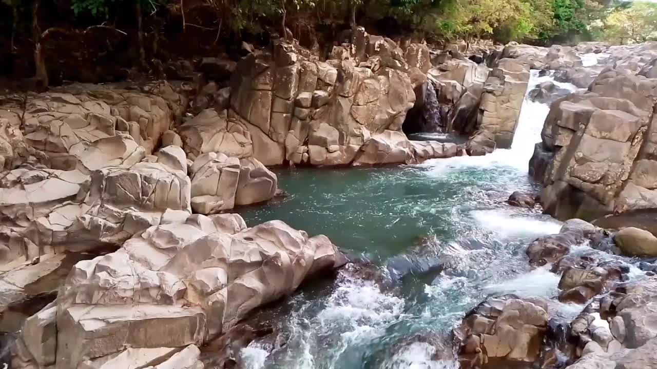 河水在有很多岩石的河流中迅速流动。它位于印度尼西亚南苏拉威西岛巴鲁的西里伯斯峡谷。新鲜的水!静态视频。视频下载