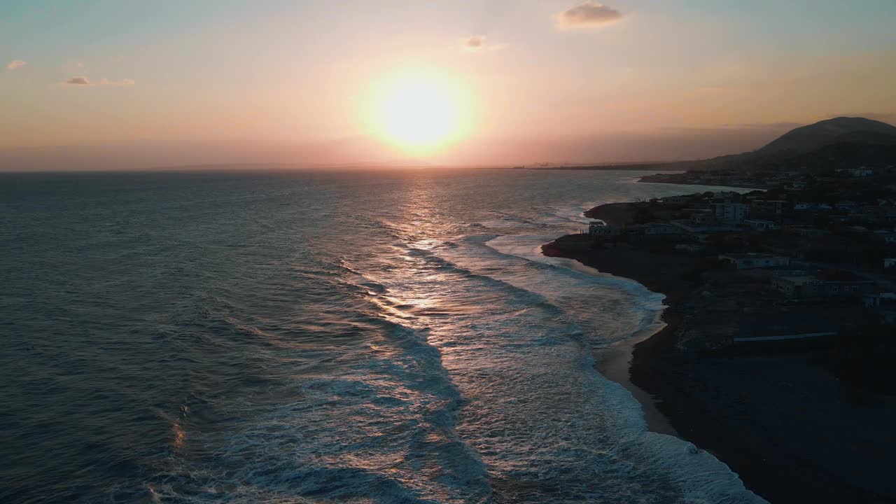 无人机景观场景的岩石山由溅起的海浪与橙色的日落场景视频素材