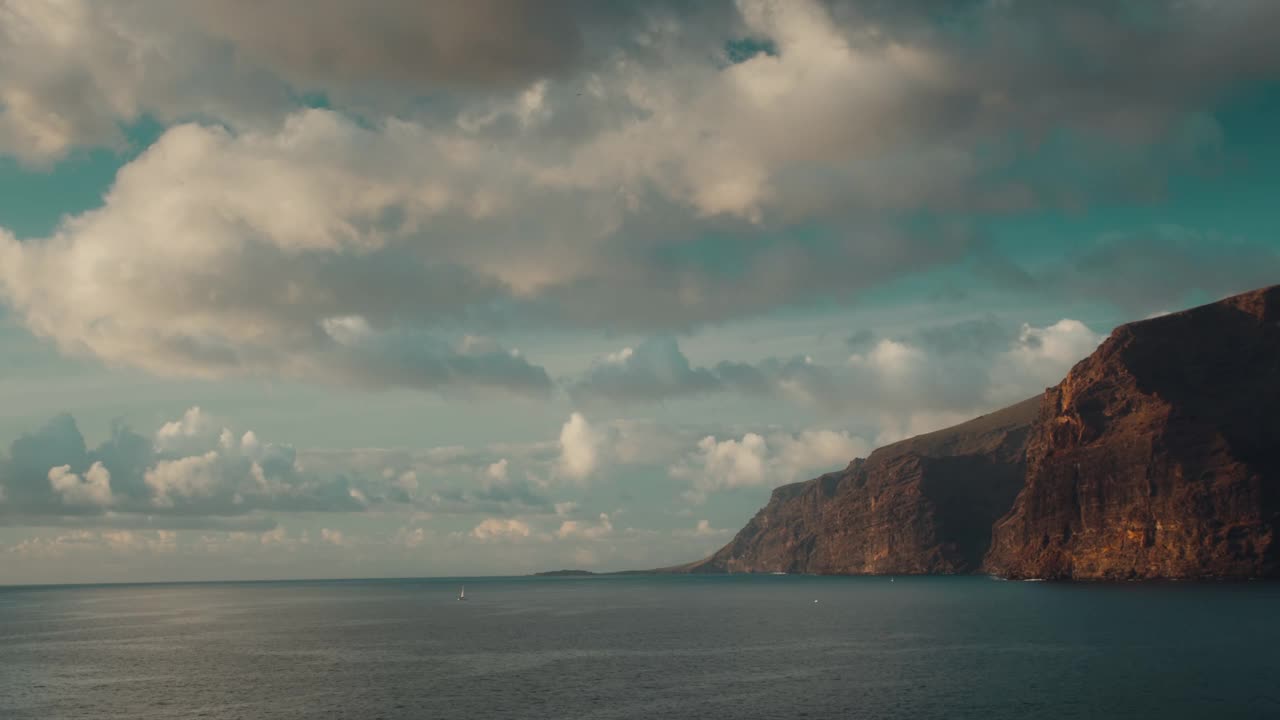 黄金时刻，多云的蓝天映衬着岩石般的海景。特内里费岛岸边黑色火山岩附近平静的海水。视频素材