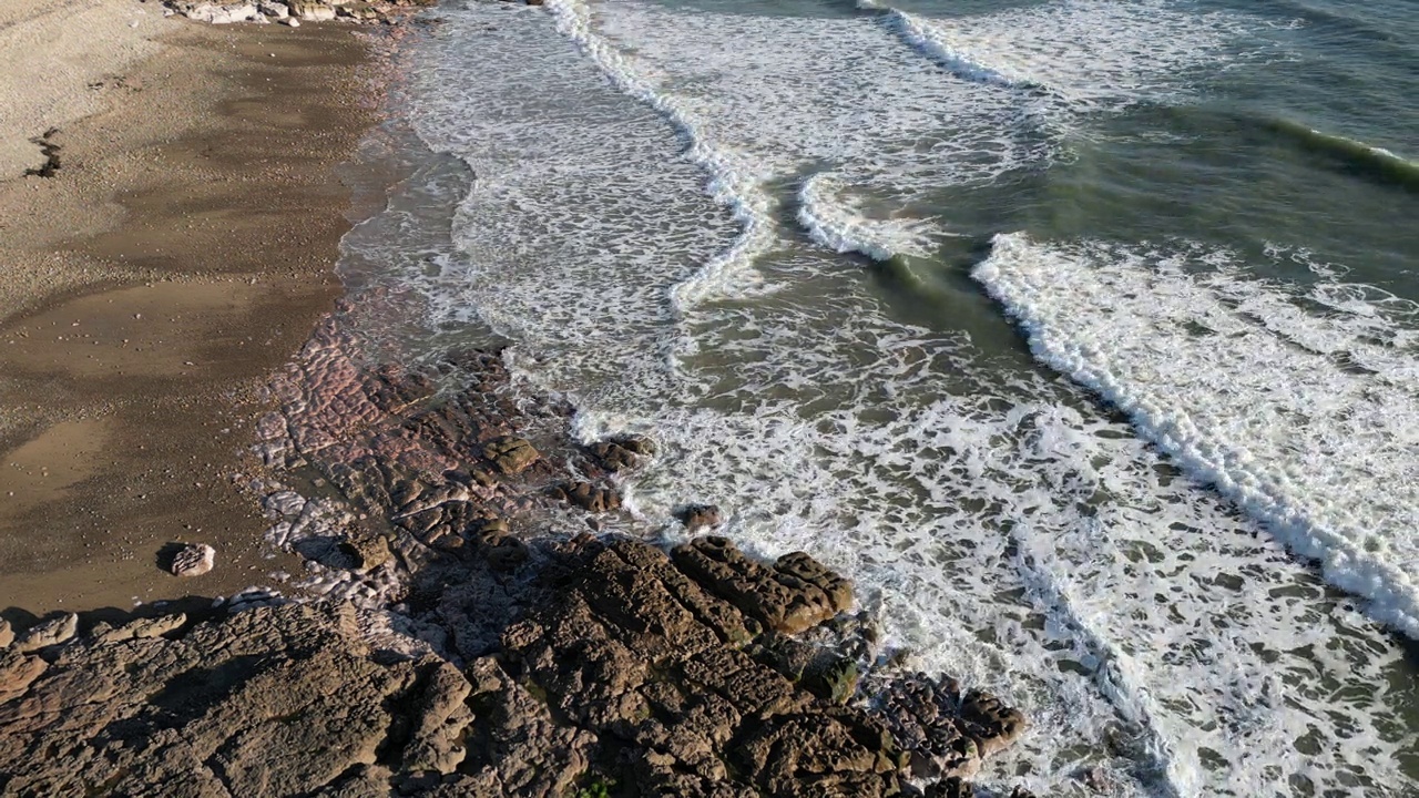 多云的天空下，海浪拍打着岩石海岸的航拍画面视频素材