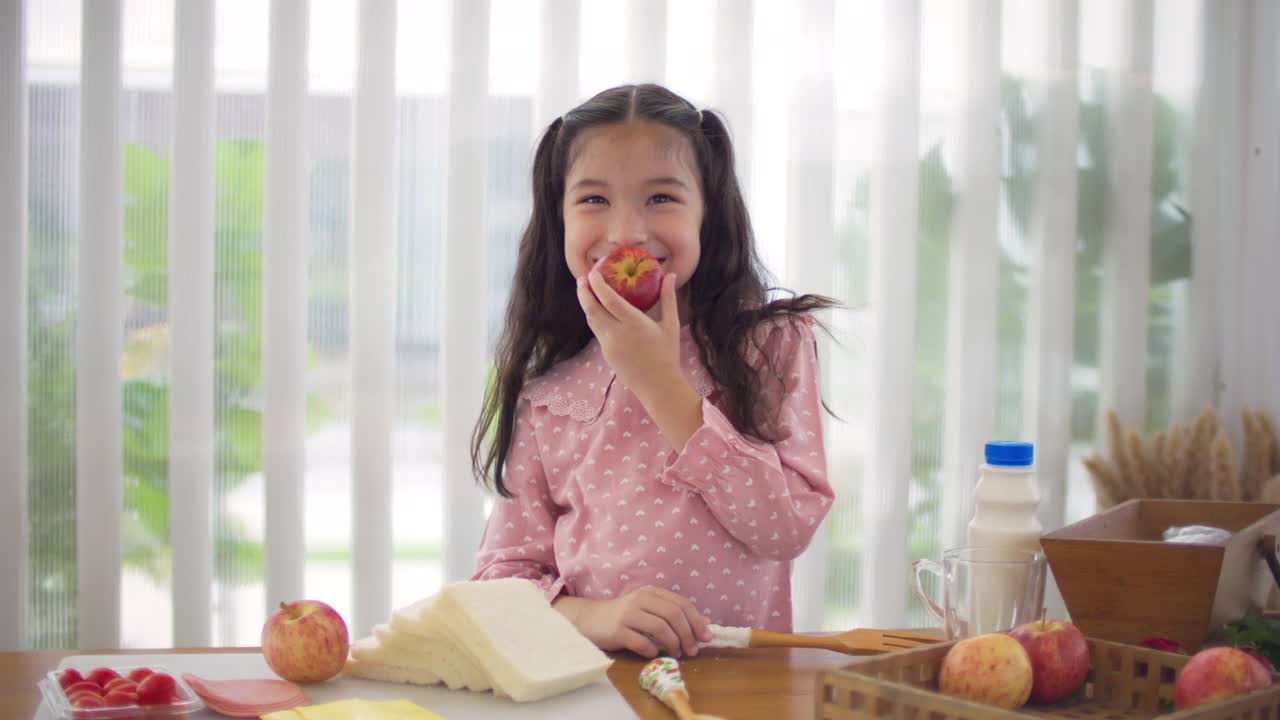 快乐的年轻亚洲女孩准备三明治视频素材