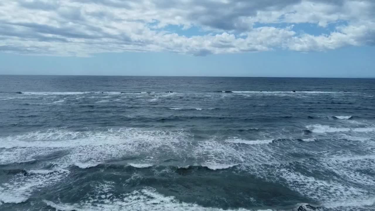 在多云的天空下，航拍蓝色大海的泡沫海浪视频素材