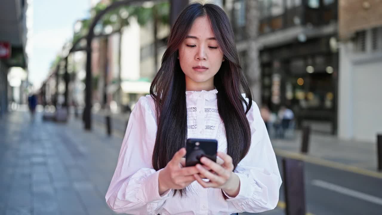 年轻的中国女子在街上用智能手机微笑视频素材