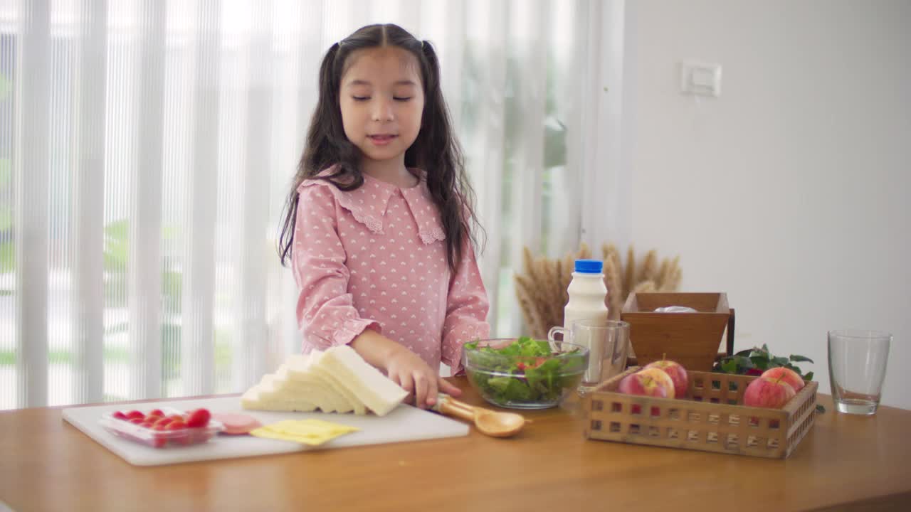 快乐的年轻亚洲女孩教如何做三明治视频素材