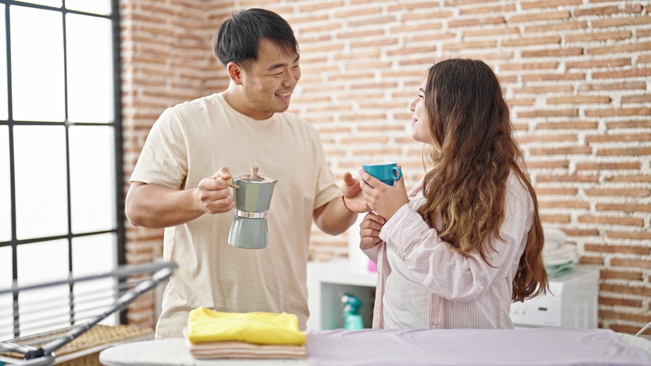 一对男女在洗衣房烫衣服喝咖啡视频素材