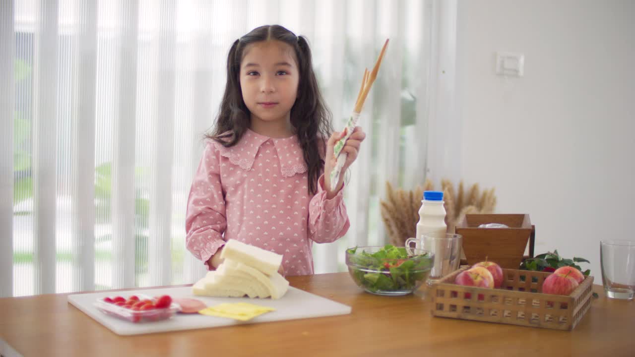 快乐的年轻亚洲女孩教如何做三明治视频素材