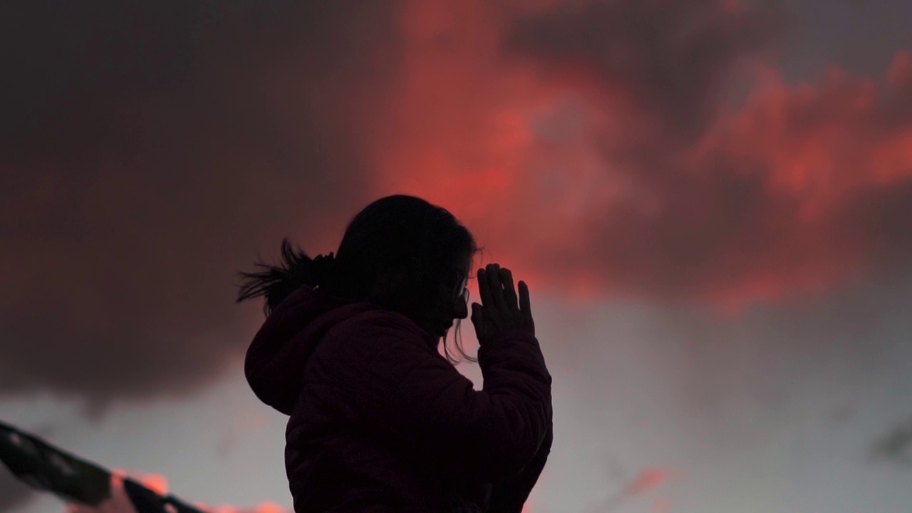 女孩祈祷的剪影。年轻女孩的背景是橙色的夕阳天空。年轻女子享受大自然，感谢上帝，这是一种宗教和信仰的概念视频素材