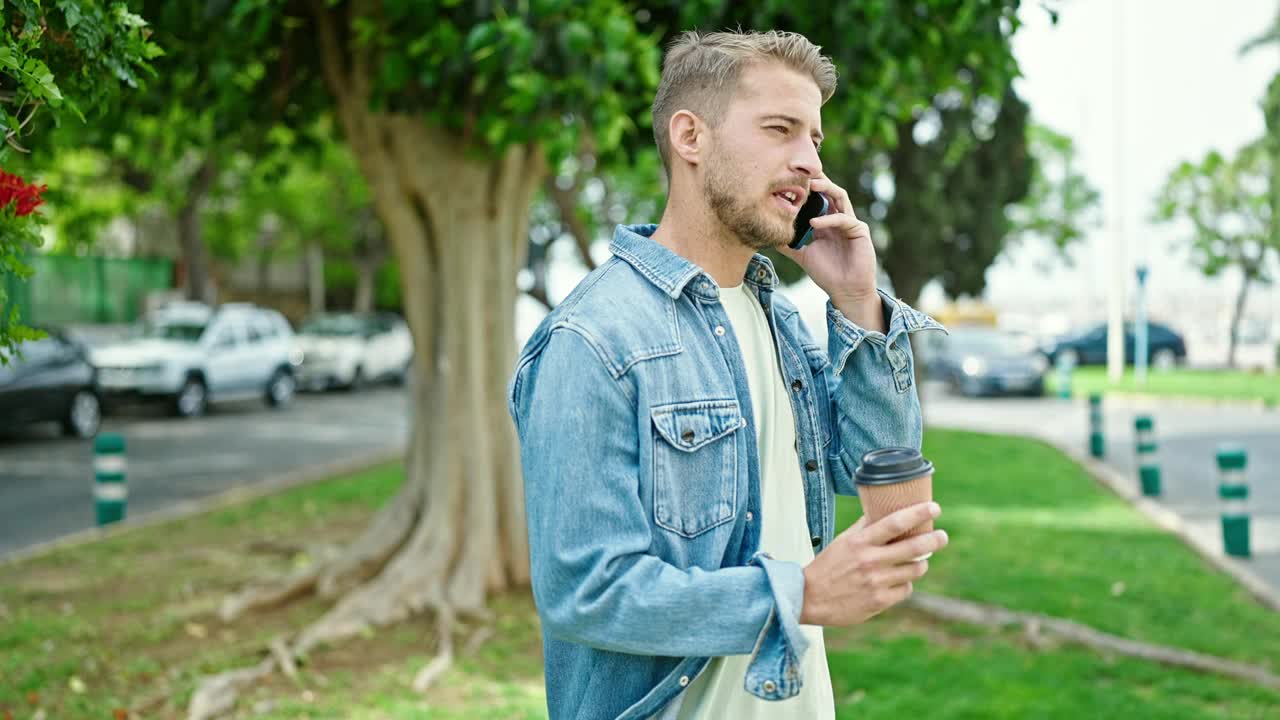 年轻的白人男子在公园用智能手机聊天喝咖啡视频素材