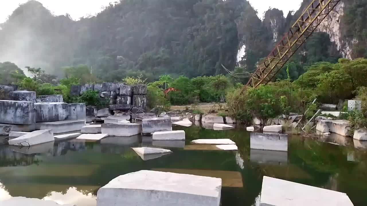 一个废弃的大理石工厂在下午的风景。有一堆方形的岩石，背景是高高的悬崖。视频下载