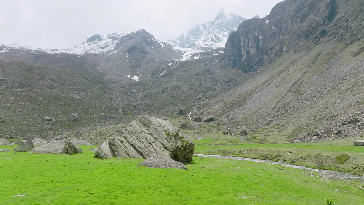 成熟的徒步旅行者爬上草地上的巨石，欣赏崎岖的山景视频下载