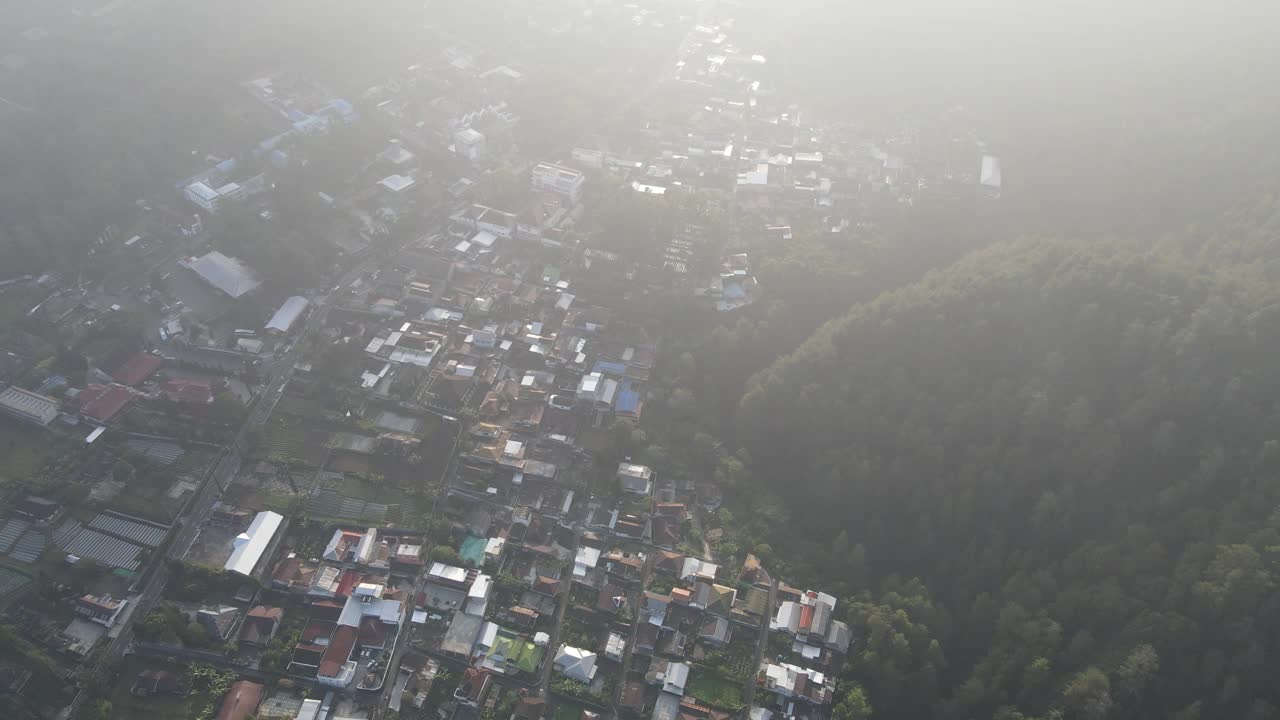 印尼村庄的早晨鸟瞰图，靠近山，有雾的景色和阳光光束。神奇的观点视频素材