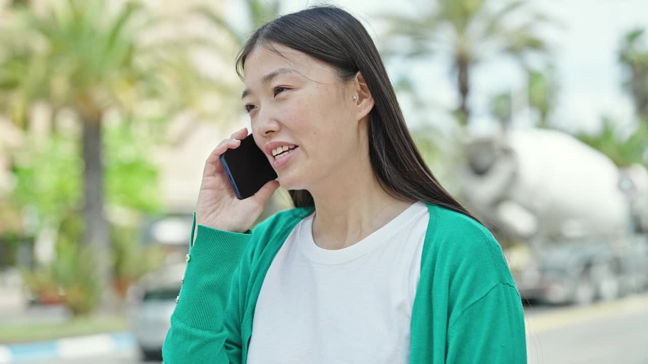 在公园用智能手机聊天的年轻中国女子微笑着视频素材