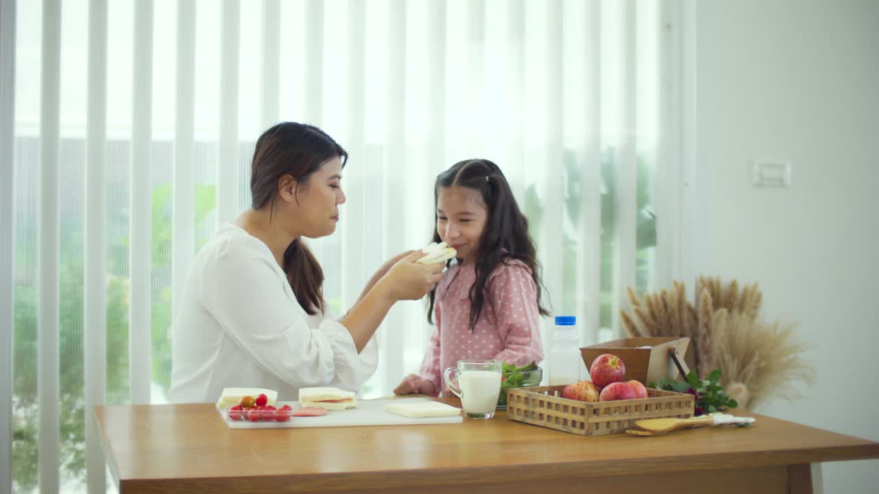 快乐的年轻母亲和女孩一起吃健康的自制三明治视频素材