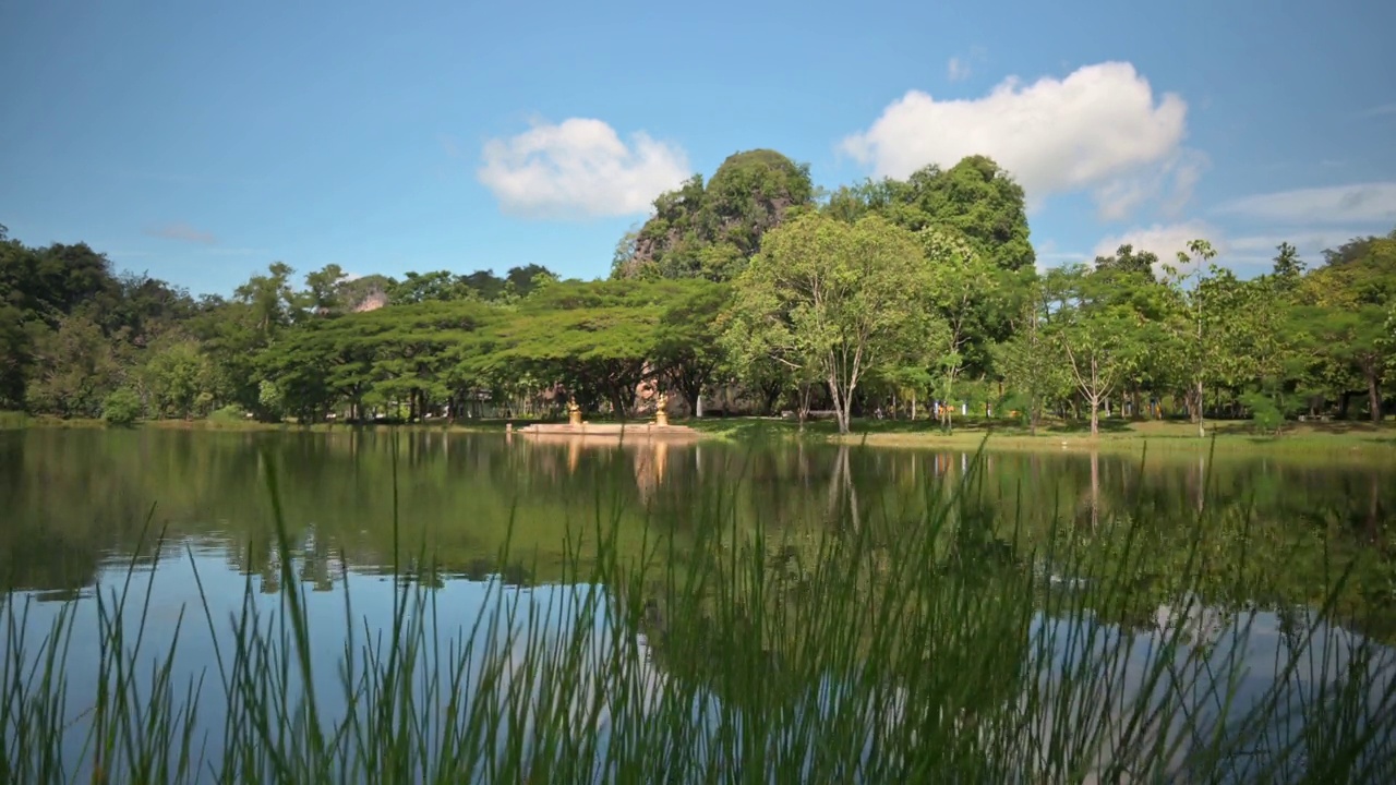 展现蓝天下的绿色公园与泻湖的美景。视频素材