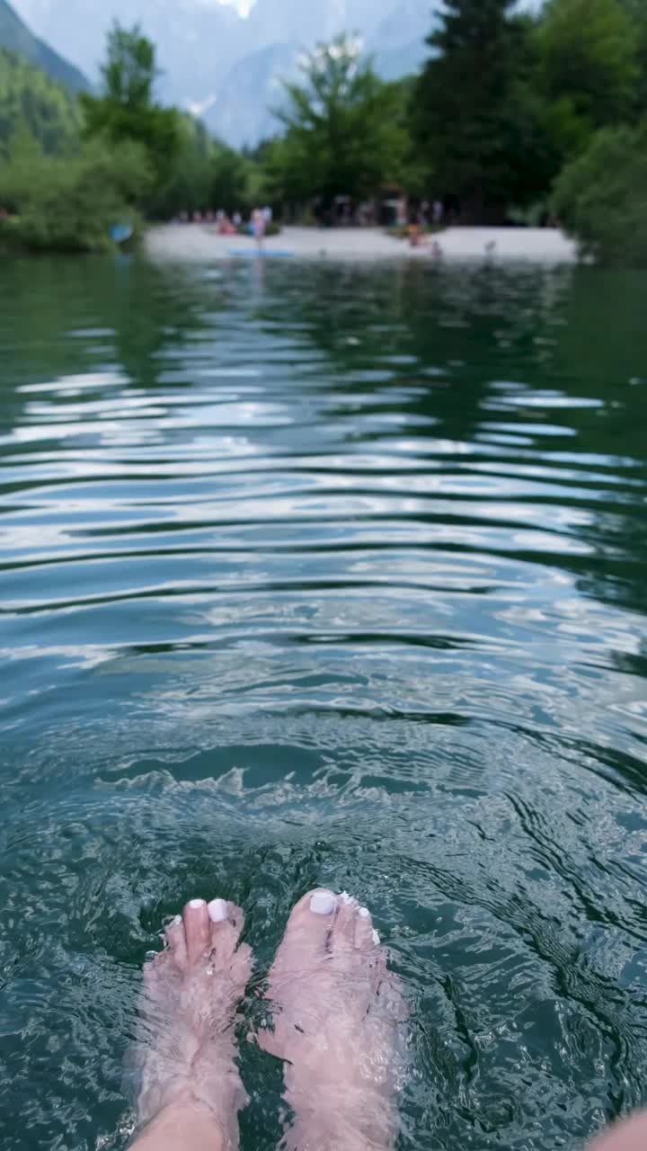 一个女人在山间的湖中泡脚。视频素材