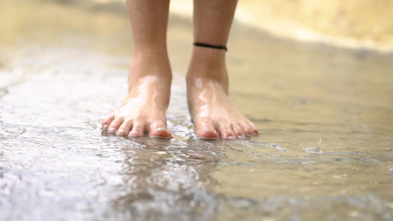 女性赤脚在雨水中跳跃的特写。视频素材