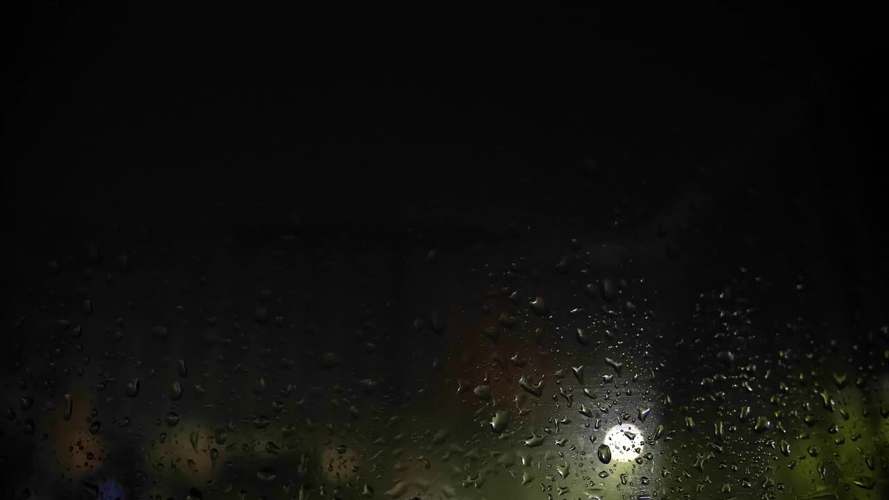 降雨的累积。滴在玻璃上。下雨了。闪电。夜晚的城市。路灯。视频素材