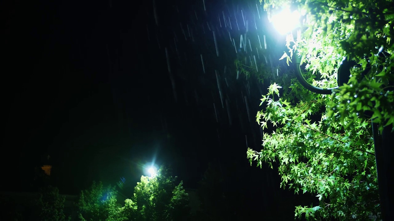 路灯。雨下降。夜里下雨了。光雨。水坑与灯光反射在城市人行道上。路灯。雨滴与路灯。特写镜头。视频素材