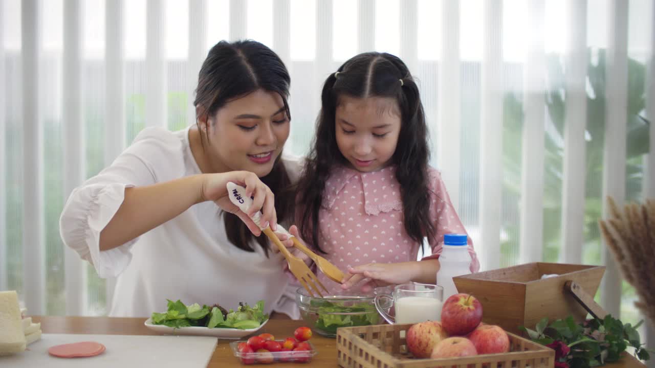 快乐的年轻母亲和女孩一起做健康的自制三明治和沙拉视频素材