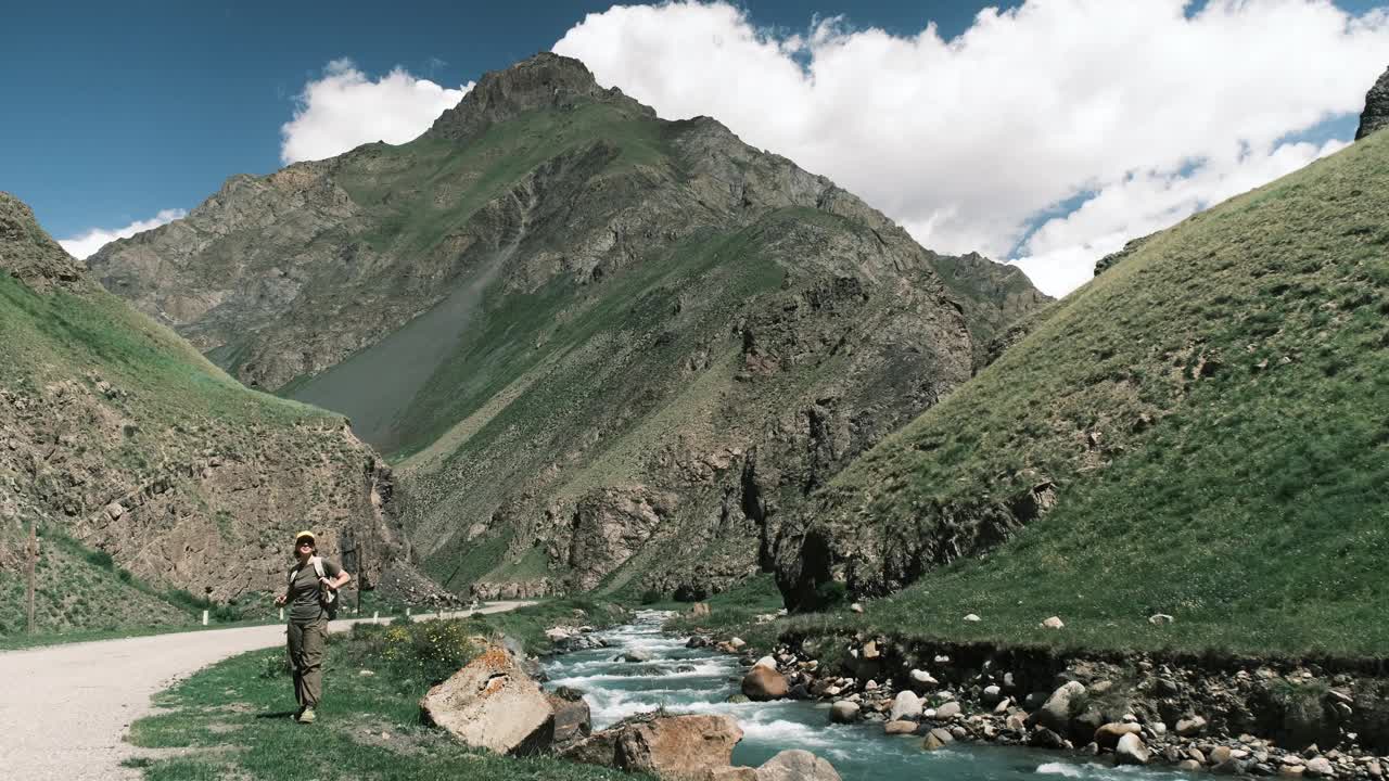 女背包客在峡谷里的山河边喝水视频素材