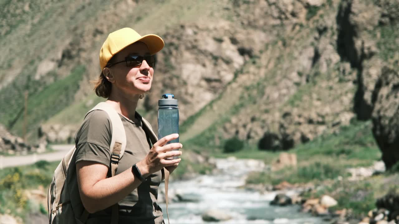 女背包客在峡谷里的山河边喝水视频素材