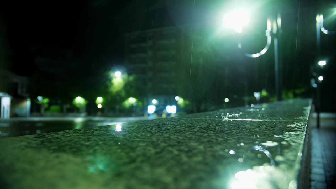 下雨了。一滩水。夜晚的城市。雨滴与路灯。特写镜头。视频素材